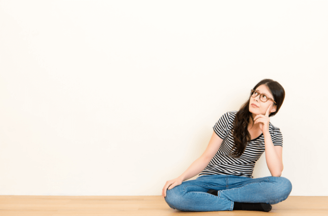 Woman sitting on floor holding her chin in an inquisitive way