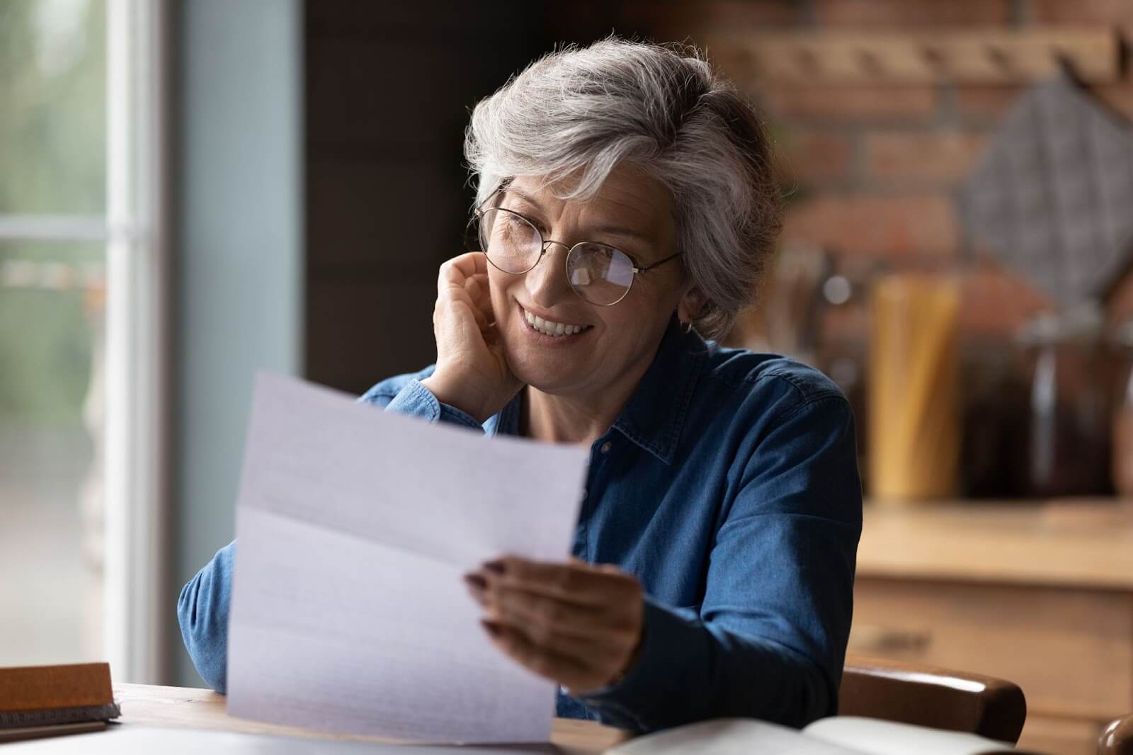 Woman sitting at kitchen table, reading credit report that she received in the mail