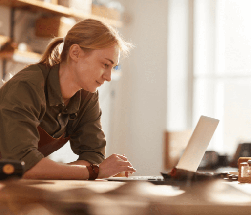 Woman in wood shop reading on her laptop