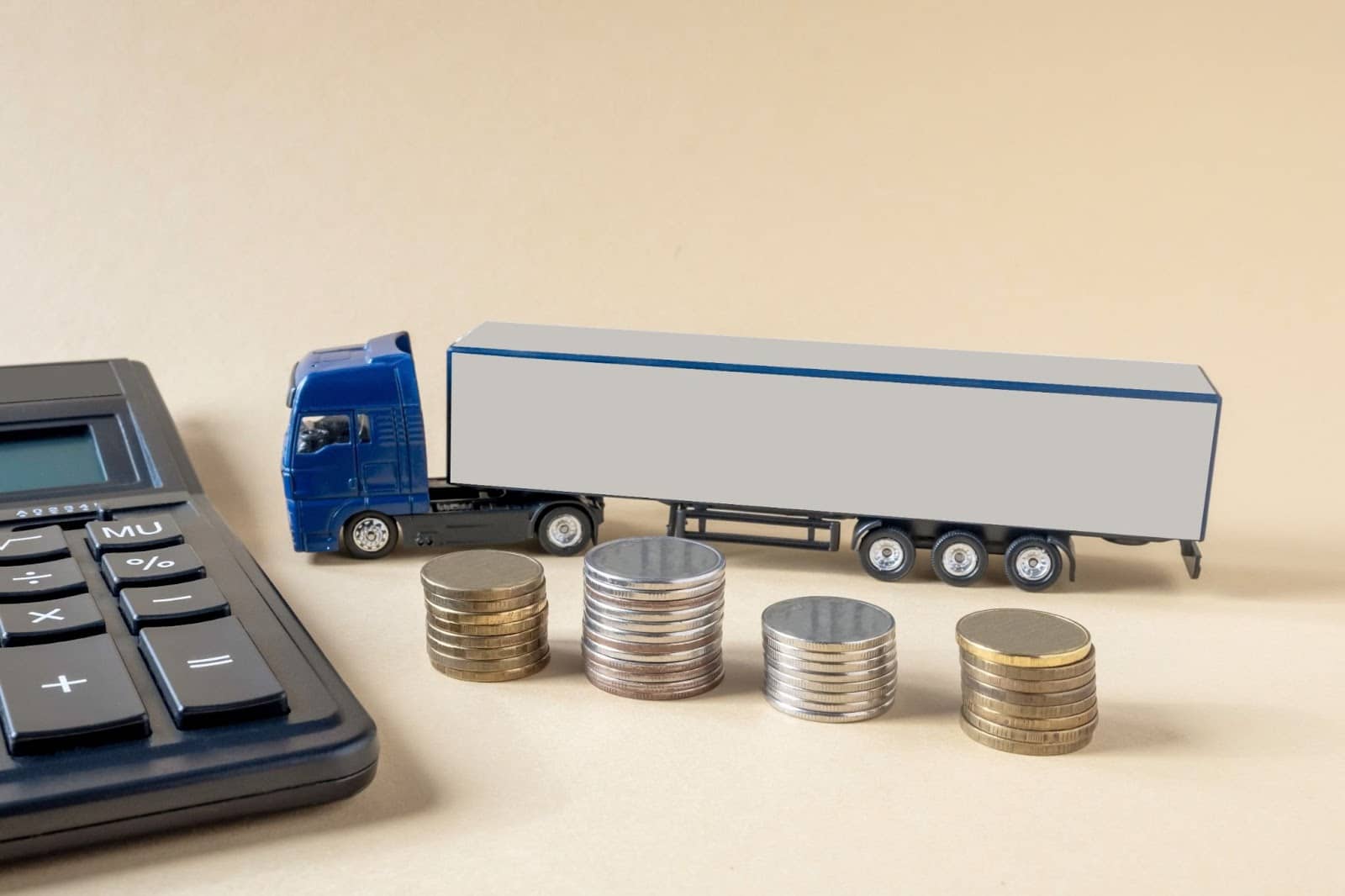 Toy truck next to calculator and stacks of silver coins